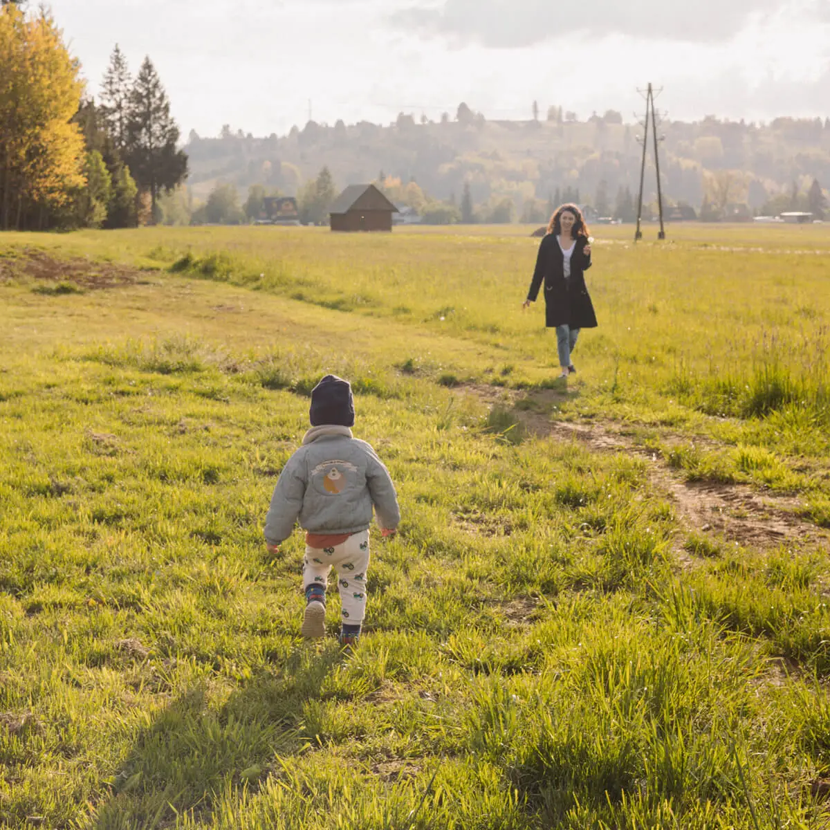 Dziecko i kobieta na polu — domki w górach
